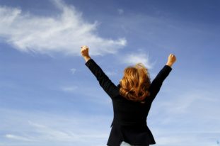 Kvinna med armarna i luften firar framgång i karriären